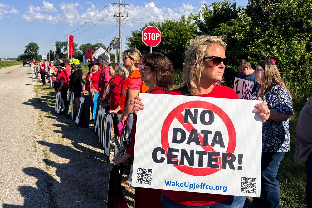 Residents holding a 'NO DATA CENTER' sign at a roadside rally